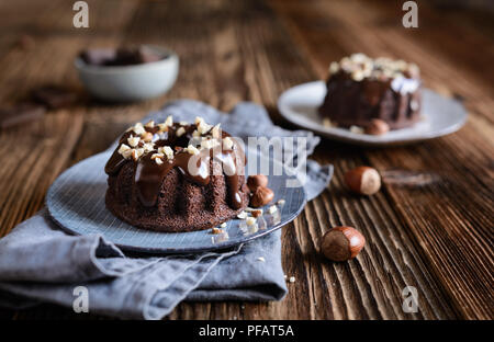 Mini Schokolade bundt Kuchen mit Glasur und gehackten Haselnüssen aufgefüllt Stockfoto