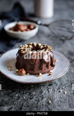 Mini Schokolade bundt Kuchen mit Glasur und gehackten Haselnüssen aufgefüllt Stockfoto