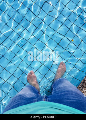 Männliche Füße mit Bräunung der Haut Eintauchen in einen Pool Stockfoto