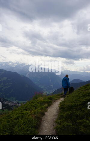 Mann und ein Berner Sennenhund, wachen auf dem Weg in den Schweizer Alpen Stockfoto