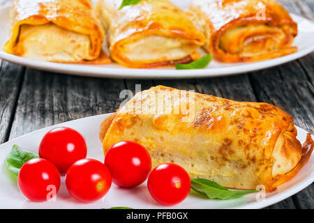 Gerollte Pfannkuchen oder Crepes gefüllt mit Hackfleisch und Gemüse auf ovalen Gerichte mit Cherry Tomaten und Basilikum serviert, Ansicht von oben Stockfoto