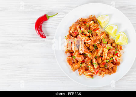 Chinesische geschmorte Schweineohren mit Gewürzen, Chili, Stücke von Kalk, bestreut mit Petersilie auf weißen dishr, Ansicht von oben Stockfoto