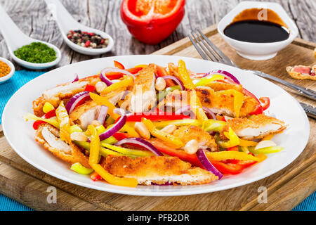 Mango, Brot panierte Hähnchenfleisch, Erdnüsse, Paprika, rote Zwiebel Salat auf einem weissen Teller, Balsamico Dressing in Soße Boote auf alten Karten, in der Nähe Stockfoto