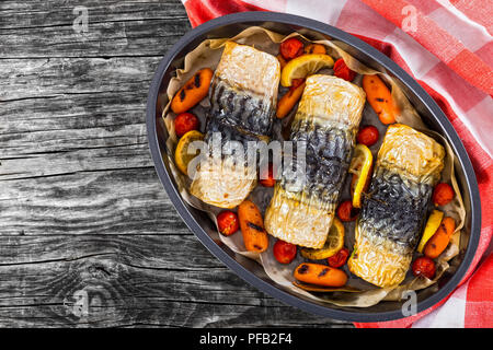 Brötchen - bis Filet Makrelen mit gegrillten Karotten, Kirschtomaten und Zitrone in Auflaufform mit karierten Küchenhandtuch auf dunklen Holzbohlen, vie Stockfoto