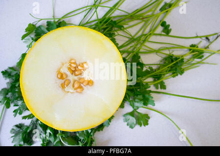 Eine halbe Galia-melone über petersilie Hintergrund. Nahaufnahme Stockfoto