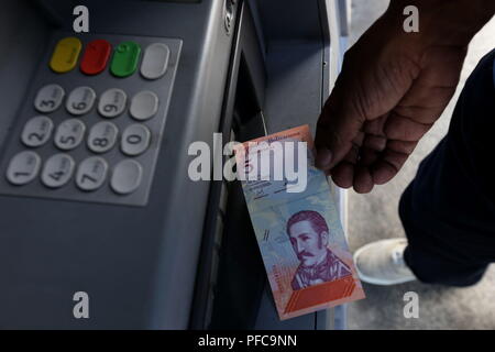 Caracas, Venezuela. 20 Aug, 2018. Ein Mann sammelt eine Rechnung von einem Geldautomaten in Caracas, Venezuela, am 12.08.20., 2018. Venezolaner begrüßte die Einführung der neuen Banknoten am Montag mit einer Mischung aus Hoffnung und Erwartung, wie die Bewegung auf die Preise auswirken wird. Die neue Sovereign Bolivar' will monetäre Transaktionen durch Abzutrennen fünf Nullen von der Bolivar, die aus dem Umlauf genommen wird, zu vereinfachen. Um mit der Funktion: Venezuelas neue Währung mit Vorfreude Credit: Gregorio Teran / AVN/Xinhua/Alamy leben Nachrichten Stockfoto