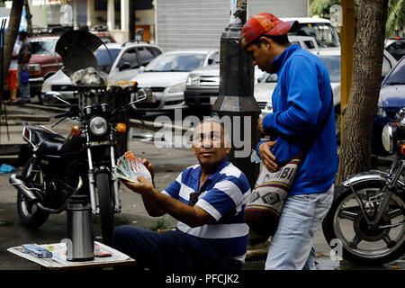 Valencia, Carabobo, Venezuela. 21 Aug, 2018. August 21, 2018. Eine street Hersteller von Kaffee zeigt einige Rechnungen der alten und der neuen geldpolitischen Kegel zirkulierenden Rechtliche in Venezuela. Die neuen Rechnungen nicht mehr die fünf Nullen, die von der Münze entfernt wurden, die in der Nutzung der alten Währung muss der Benutzer die direkte Umstellung tun und wissen, dass Er hat fünf Nullen weniger als sein Wert. In Valencia, Carabobo Zustand. Foto: Juan Carlos Hernandez Credit: Juan Carlos Hernandez/ZUMA Draht/Alamy leben Nachrichten Stockfoto