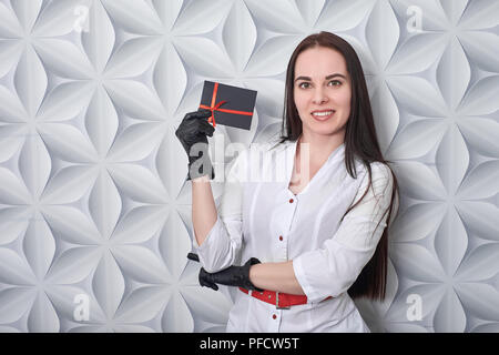 Arzt in einem medizinischen Kleid zeigt eine Geschenkkarte Stockfoto
