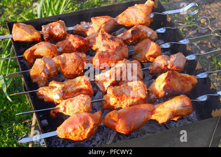 Lecker saftig gegrillten Schaschlik oder mariniertes Fleisch auf Metall Spieße auf Grill im Garten, Blick von oben, close-up Stockfoto