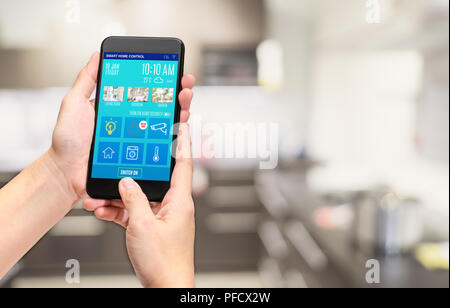 Hand, die den mobilen Einsatz smart home Control mobile App an Blur bokeh Küche Hintergrund, Smart Living Konzept, digitalen Lifestyle. Stockfoto