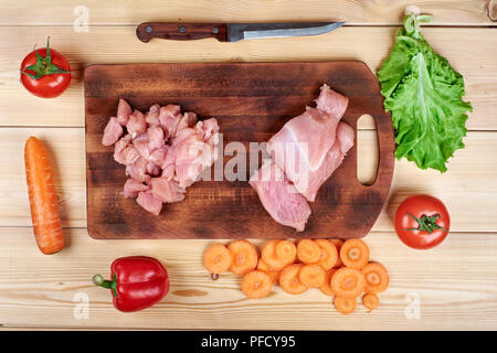 Blick von oben auf die Vorbereitung Schneiden frisches rohes Huhn mit Gemüse. Stockfoto
