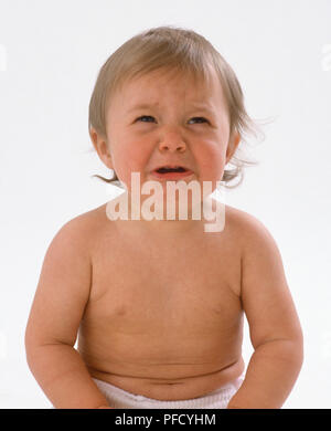 Baby Windeln tragen, sitzen auf dem Boden und schrie, miserable Ausdruck, den Mund offen, oben zu schauen. Stockfoto