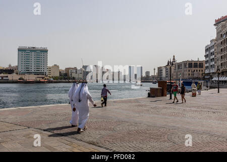 Zwei arabische Männer in traditionellen Emiratische Kleid zu Fuß entlang des Dubai Creek im Stadtteil Bur Dubai, Vereinigte Arabische Emirate. Stockfoto