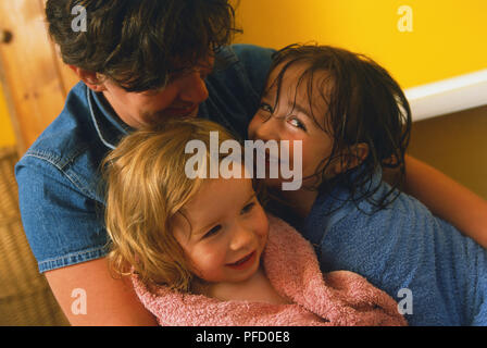 Zwei lächelnde junge Mädchen in Handtücher umarmte durch Frau eingehüllt. Stockfoto
