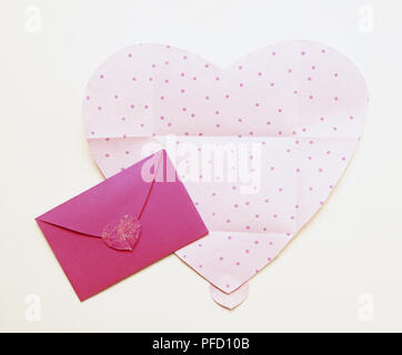 Schnitt aus blass rosa Herz mit Punkten, und kirschrot Umschlag befestigt mit roten Herzen ausschneiden Stockfoto