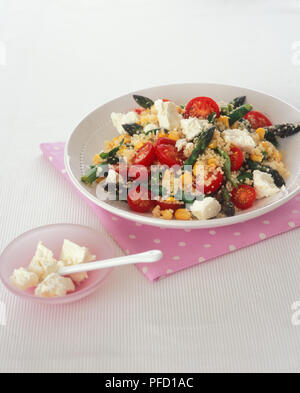 Schüssel mit gedämpften Couscous mit Frühlingsgemüse und Feta Käse, auf eine Serviette und eine kleinere Schüssel mit Feta Käse Stockfoto