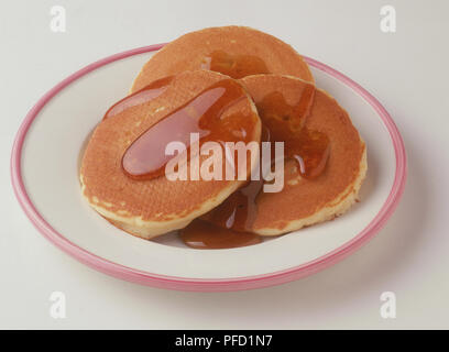 Pfannkuchen mit Ahornsirup, serviert auf einem Rosa - eingefaßte weiße Platte, hohen Winkel betrachten. Stockfoto