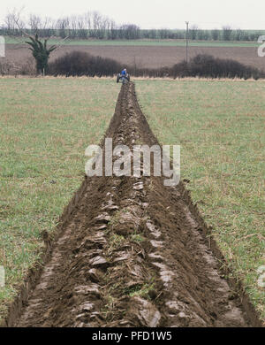 Landwirt mit Traktor Pflug Furchen in das Feld ein. Stockfoto