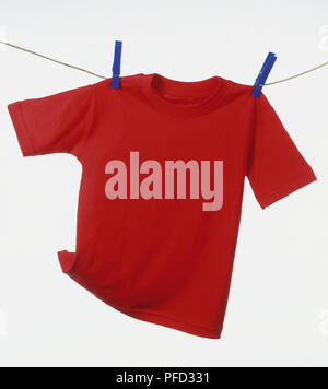 Red-Shirt hängen auf Wäscheleine, zwei blaue Wäscheklammern auf beiden Seiten Stockfoto