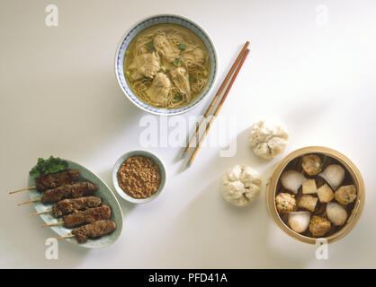 Kantonesische Wan-tan Suppe, Auswahl an Dim Sum, Satay und Erdnuß-Sauce, und ein Paar Stäbchen, Ansicht von oben Stockfoto