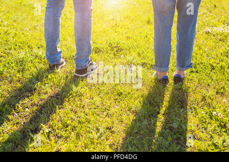 Reisen zusammen Konzept - stilvolles Paar Beine an sonnigen Gras in der Wiese im Sommer Stockfoto