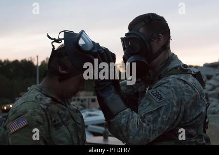 Gemeinsame Basis CAPE COD, Massachusetts-Spezialist Connor Oriordan, einem chemischen, biologischen, radiologischen und nuklearen Facharzt mit der 272 Chemical Company Massachusetts Army National Guard, entfernt ein Gas Maske von einem Soldaten. Die Schulung ist Teil einer kombinierten Waffen ausüben, welche Tests die Mission Bereitschaft der Combat support Einheiten hier Juni 10, 2018. (Massachusetts Army National Guard Stockfoto