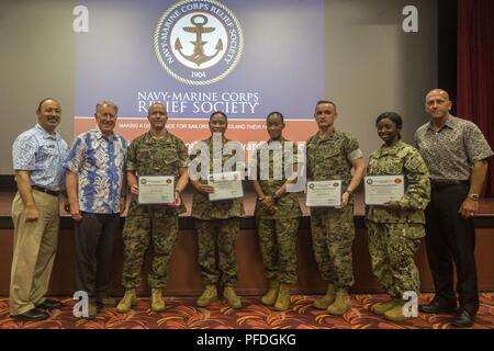 Service Mitglieder pose mit Auszeichnungen neben Personal mit Navy-Marine Corps Fhv (NMCRS) und Douglas Wadsworth, Stabschef, Marine Corps Base Hawaii (MCBH) während der NMCRS Active Duty Kapital Antrieb Preisverleihung, an der Basis Theater, MCBH, 11. Juni 2018. Die NMCRS bietet finanzielle Entlastung in den aktiven Dienst und im Ruhestand Marinesoldaten und Matrosen sowie deren berechtigte Hinterbliebene durch zinslose Darlehen und Zuschüsse. Stockfoto