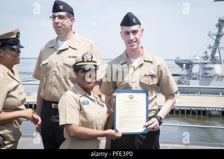 NORFOLK, Virginia (8. Juni 2018) - Elektroniker 3. Klasse Daniel Woodburn, von Klee, Südcarolina, USS Gerald R. Ford's (CVN 78) Combat Systems Abteilung zugewiesen, erhält seine Ernennungsurkunde in den Rang eines Petty Officer third Class von Lt.Cmdr. Satonya Braun, Combat Systems Wartung Ford's Officer, während der Werbeaktion Zeremonie an Bord des Schiffes. Stockfoto