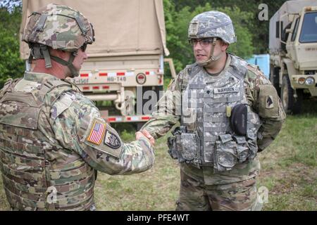 CAMP ÄSCHE, Mich-Command Sgt. Maj. Tyson Johnston, der 81St Truppe Befehl älterer Soldat Führer, stellt SPC. Phillip Mahurin, ein Spezialist der 2-150 th Field Artillery Regiment mit einer Münze in Anerkennung weit über die Grenzen hinausging, während der jährlichen Schulung der Einheit im Camp Äsche, Mich. 7. Juni 2018. Mahurin war für Hand anerkannten basteln eine Flagge stehen für die Einheit, wenn man nicht verfügbar war. Stockfoto