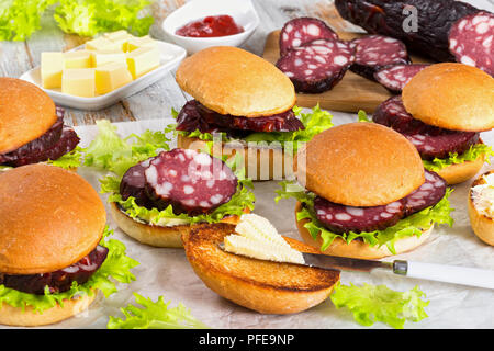 Köstliche Sandwiches mit Butter, Salat und geräucherte Wurst 2-in-1 von Bun auf weißem Pergamentpapier, Butter Würfel, Tomatensauce und Stick von Wurst Stockfoto