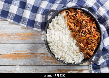 Langsam zog gekochte Schweineschulter vom Grill im Backofen mit langkörniger Basmati Reis in Eisen stewpot mit Küchentuch, auf Holz- Tabelle, Ansicht von oben Stockfoto