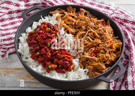 Langsam zog - gekocht köstliche würzige Fleisch mit Reis und Bohnen herzhafte Salsa bestreut mit Frühlingszwiebeln in stewpot mit Küchentuch, auf Holztisch, Cl Stockfoto