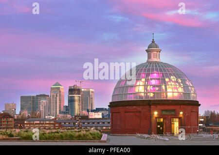 LONDON, Großbritannien - 13 Dezember: Greenwich unterführung Eingang am frühen Morgen, mit Canary Wharf Wolkenkratzer in den Hintergrund und rosa getönte Wolken im Stockfoto
