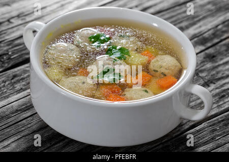 Köstliche organische Hühnersuppe mit Fleischbällchen, Karotten und Kartoffeln mit Petersilie bestreut im Doppelzimmer behandelt Soup Bowl auf alten Holztisch, close-up Stockfoto