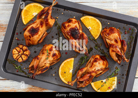 Ganze Wachteln mariniert mit Sojasauce, Honig, Knoblauch und orange, gegrillte beim Rösten Gericht mit Thymian, Ansicht von oben, close-up Stockfoto