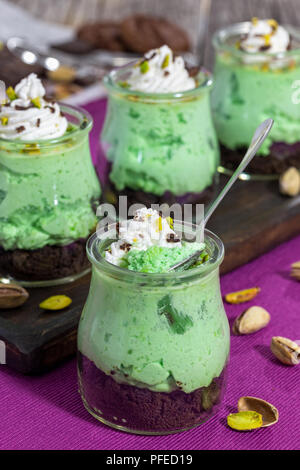Pistazien aero Mousse und Schokolade Cookies keine Backen Dessert in kleinen Gläsern, einfaches Rezept, Nahaufnahme, vertikale Ansicht von oben Stockfoto