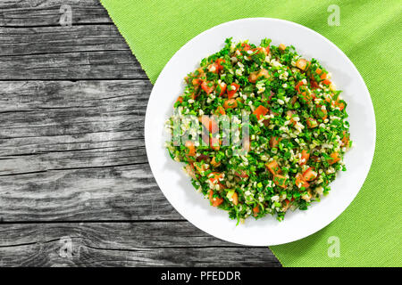Petersilie Salat oder Tabbouleh auf weiße Platte, einfache und gesunde Classic vegetarisches Gericht mit Bulgur, Tomaten, Petersilie, Frühlingszwiebeln und Minze, Olivenöl Stockfoto