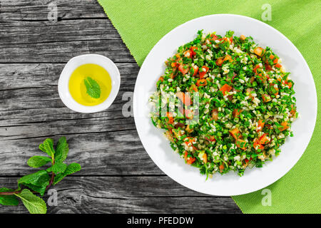 Petersilie Salat oder Tabbouleh auf weiße Platte, einfache und gesunde Classic vegetarisches Gericht mit Bulgur, Tomaten, Petersilie, Frühlingszwiebeln und Minze, Olivenöl Stockfoto