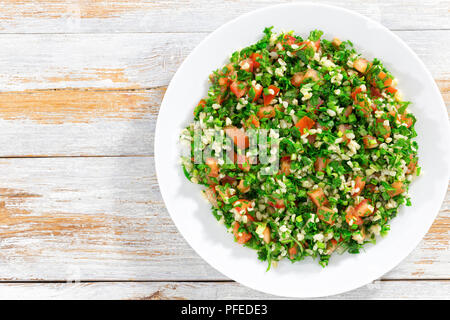 Petersilie Salat oder Tabbouleh auf weiße Platte, einfache und gesunde Classic vegetarisches Gericht von Bulgur, Tomaten, Petersilie, Frühlingszwiebeln und Minze auf Holz- b Stockfoto