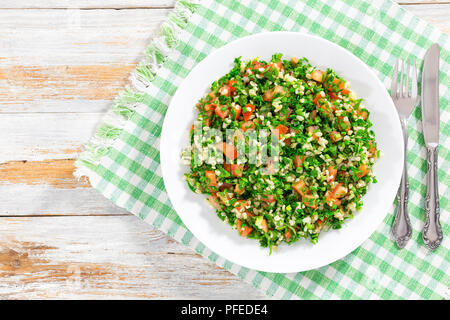 Petersilie Salat oder Tabbouleh auf weiße Platte, einfache und gesunde Classic vegetarisches Gericht von Bulgur, Tomaten, Petersilie, Frühlingszwiebeln, Ansicht von oben Stockfoto