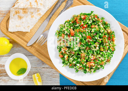 Petersilie, Minze, Tomate, Salat oder Tabbouleh auf weißem platter auf Schneidebrett, einfache und gesunde Classic vegetarisches Gericht, Olivenöl und Zitrone Slices auf o Stockfoto