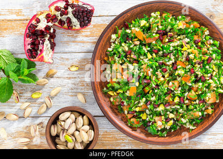 Lecker tabbouleh Salat mit Granatapfel, Pistazien, Petersilie, Pfefferminze, Frühlingszwiebeln, Tomaten, beträufelt mit Zitronensaft und Olivenöl, Nahaufnahme, Stockfoto