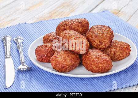 Saftig lecker gebratenes Fleisch Schnitzel auf weißem Platter am Küchentisch Matte, Ansicht von oben, close-up Stockfoto