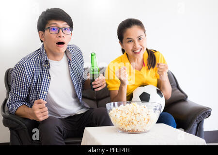 Asiatische Fußball-Anhänger Gruppe der Freund gerade Fußball-Sport Match auf tv und jubeln, Feiern mit Bier und Popcorn zu Hause mit Spaß oder disapp Stockfoto