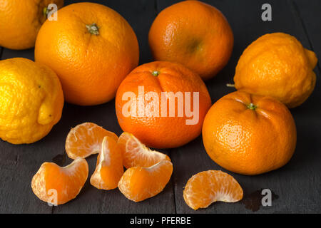Zitrusfrüchte Hintergrund mit Orangen-, Mandarinen- und Zitronenbäumen Obst auf rustikalen schwarz Tischplatte Stockfoto