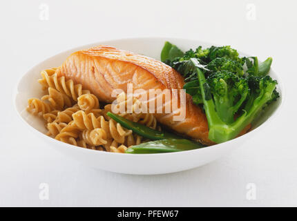 Lachs mit Brokkoli, mangetout und grunchy Pasta, in zarten, weißen Keramik Schüssel serviert. Stockfoto