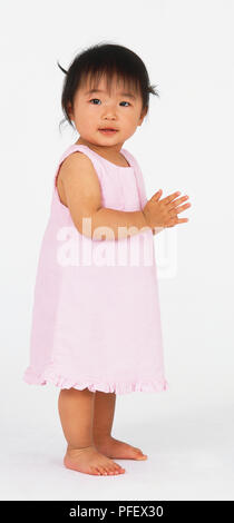 Girl Toddler in rosa Kleid stehen und seitlich, Seitenansicht Stockfoto