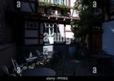 Stühle und Tische im Innenhof eines Fachwerkhauses in Bacharach, Deutschland. Stockfoto