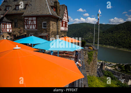 Ein Tourist aus blicken Sie auf den Rhein unter bunten Sonnenschirmen auf Burg Stahleck in Bacharach, Deutschland. Stockfoto