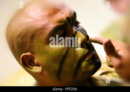 Ein Fallschirmjäger der US-Armee zur 1. Bataillon zugeordnet, 503Rd Infanterie Regiment, 173Rd Airborne Brigade setzt den letzten Schliff zu Ihrem Gesicht Farbe Camouflage bei Aviano Air Base in Vorbereitung auf die Übung Bajonett Streik Westen auf Casa De Campos Drop Zone in Spanien, 12. Juni 2018. Bajonett Streik West ist ein bilaterales Training zwischen US-Fallschirmjäger zu 173Rd Airborne Brigade und der Spanischen Airborne Brigade, die zur Verbesserung der NATO-operativer Standards und der Entwicklung von individuellen technischen Fertigkeiten Schwerpunkt zugeordnet. Die 173Rd Airborne Brigade ist der US-Armee Contingency Response Force in Europ Stockfoto